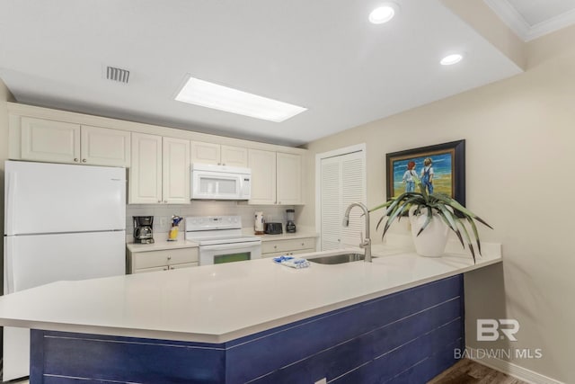 kitchen with light countertops, visible vents, a sink, white appliances, and white cabinetry