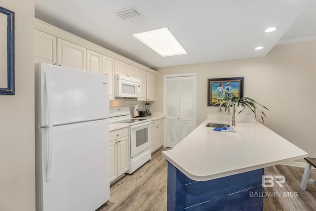 kitchen with visible vents, white appliances, a sink, and light wood finished floors