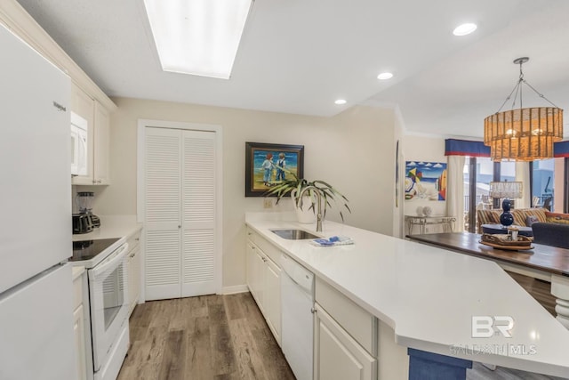 kitchen featuring a sink, white appliances, light wood-type flooring, an inviting chandelier, and white cabinets