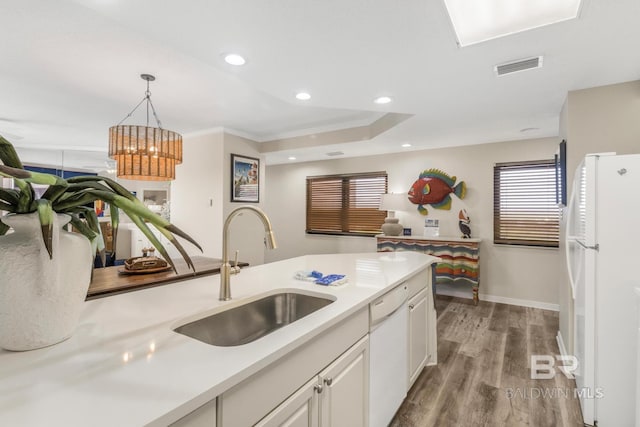 kitchen featuring light countertops, visible vents, a sink, and white appliances