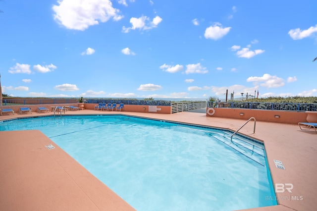 view of swimming pool featuring fence and a patio area