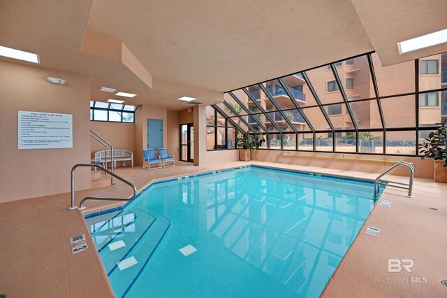 pool with a patio area and glass enclosure