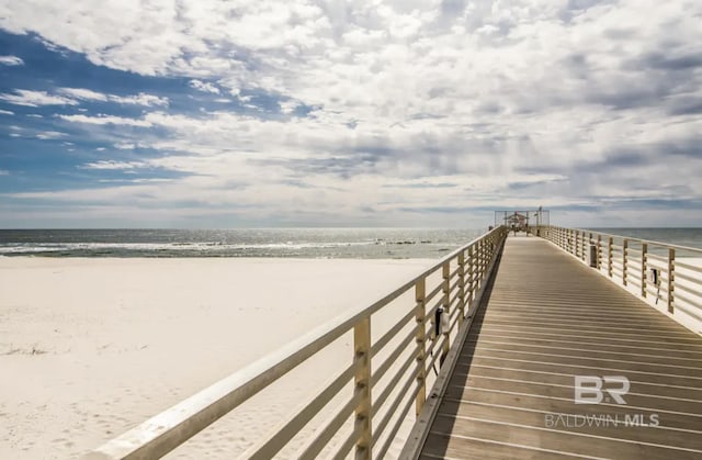 view of dock with a beach view and a water view