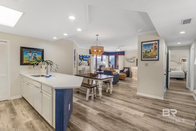 kitchen featuring white cabinets, a peninsula, baseboards, visible vents, and light wood-style floors