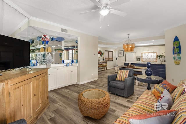 living area featuring wood finished floors, visible vents, and crown molding