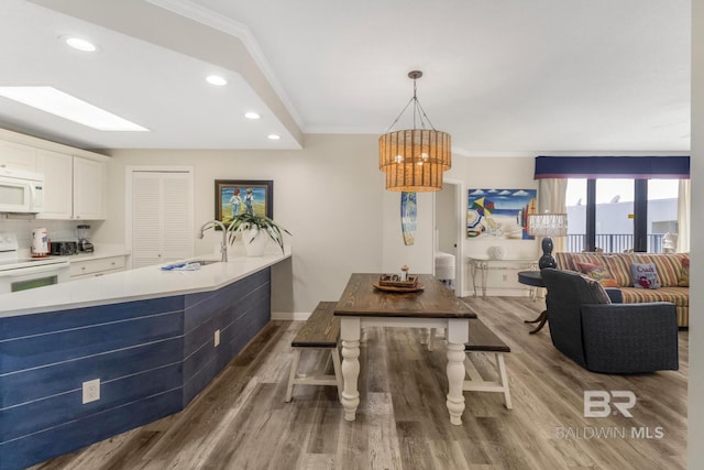 dining area with a notable chandelier, wood finished floors, baseboards, ornamental molding, and recessed lighting