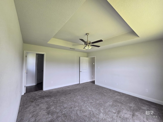 23035 Ridgewood Dr, Robertsdale, AL 36567 - unfurnished bedroom with a tray ceiling, dark carpet, ceiling fan, and a textured ceiling