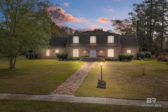view of property featuring a shingled roof, mansard roof, and brick siding