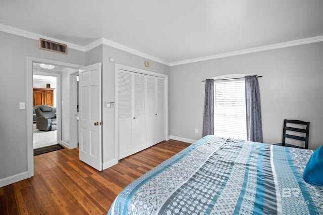 bedroom with visible vents, crown molding, wood finished floors, baseboards, and a closet