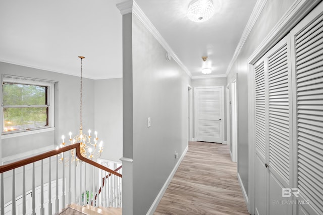 hall featuring a chandelier, crown molding, baseboards, an upstairs landing, and light wood-style flooring