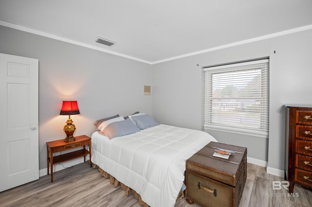 bedroom featuring visible vents, ornamental molding, light wood finished floors, and baseboards