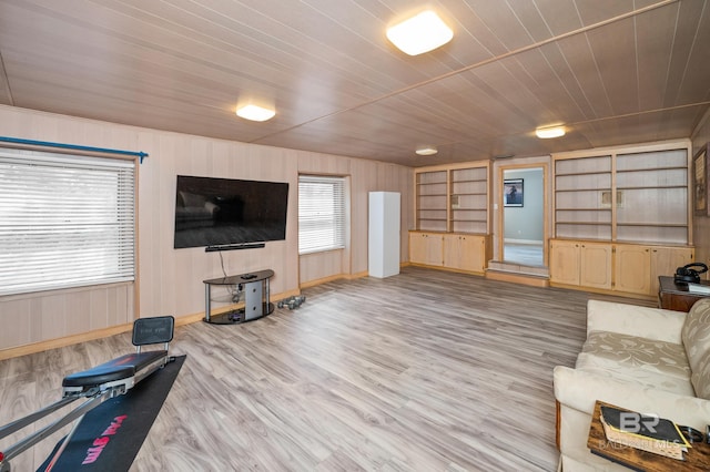 living area featuring built in features, wood finished floors, baseboards, wooden walls, and wooden ceiling