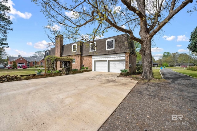 view of front facade with a garage, brick siding, mansard roof, concrete driveway, and a shingled roof