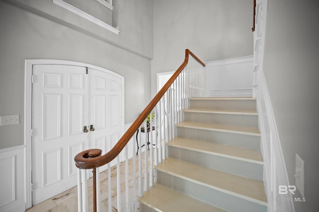 stairway featuring wainscoting and a decorative wall