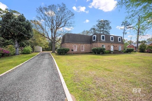 front facade with an outdoor structure, a front lawn, a shed, and brick siding