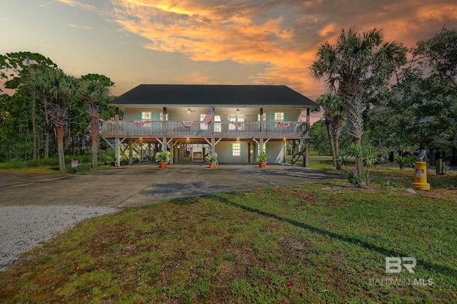 coastal inspired home featuring a carport, covered porch, driveway, and a front lawn