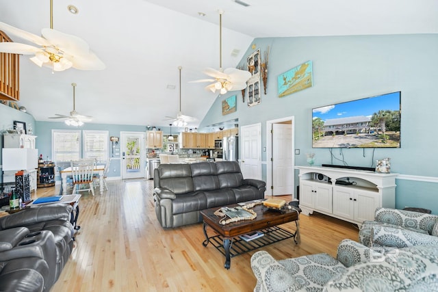 living room with high vaulted ceiling, ceiling fan, and light hardwood / wood-style flooring