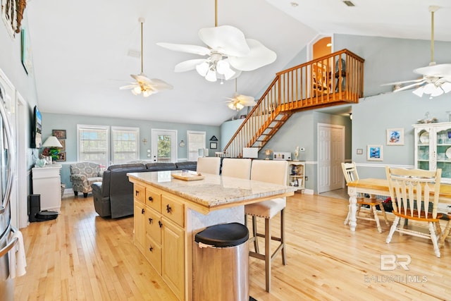 kitchen with a breakfast bar, a center island, high vaulted ceiling, light wood-type flooring, and ceiling fan