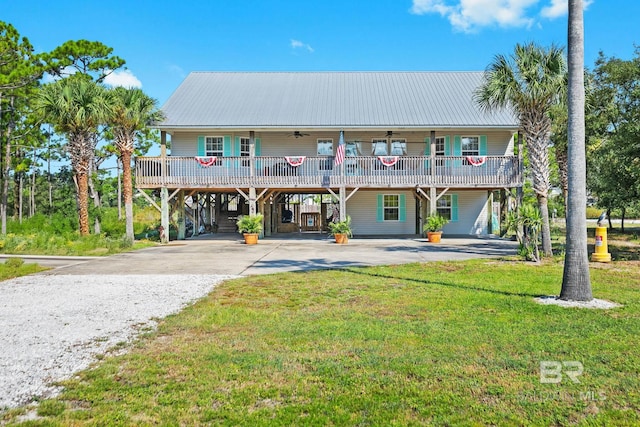 view of front of house with driveway, metal roof, a front lawn, and a ceiling fan