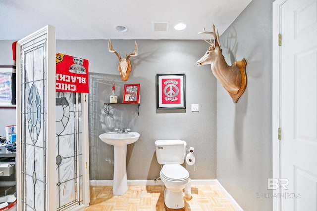 bathroom featuring sink, parquet flooring, and toilet