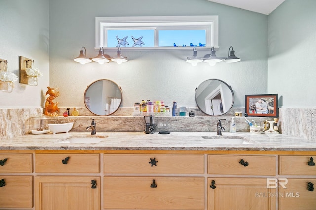 bathroom featuring lofted ceiling, double vanity, and a sink