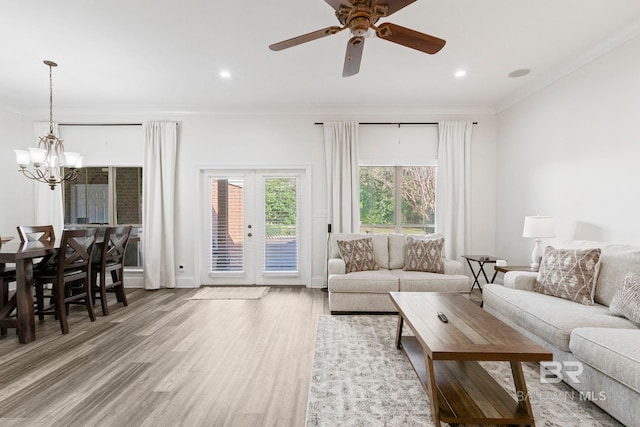 living room featuring french doors, wood-type flooring, ceiling fan with notable chandelier, and ornamental molding