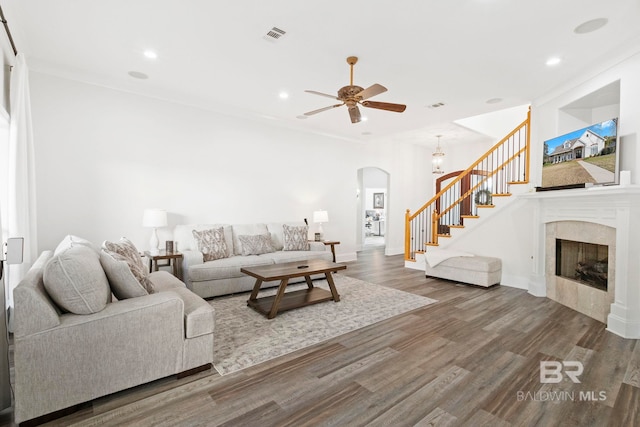 living room featuring a tiled fireplace, ceiling fan, ornamental molding, and hardwood / wood-style flooring