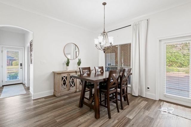 dining area featuring crown molding, dark wood-type flooring, and a notable chandelier