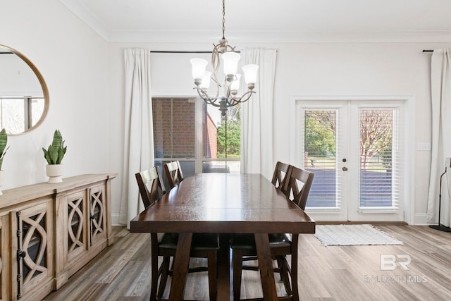 dining area with french doors, crown molding, a notable chandelier, and hardwood / wood-style floors