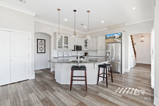 kitchen with tasteful backsplash, dark stone countertops, decorative light fixtures, white cabinets, and appliances with stainless steel finishes