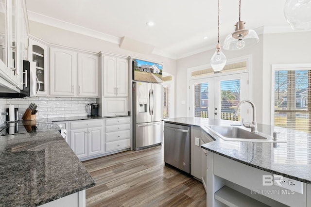 kitchen with sink, appliances with stainless steel finishes, tasteful backsplash, decorative light fixtures, and white cabinetry