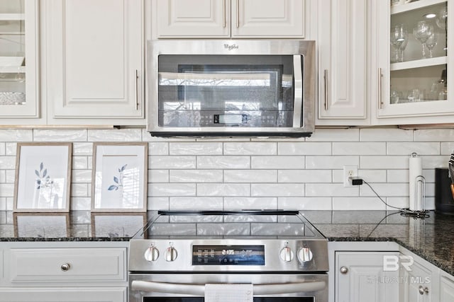 kitchen featuring white cabinets, decorative backsplash, dark stone countertops, and appliances with stainless steel finishes