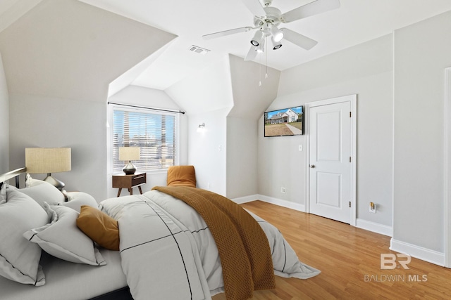 bedroom with ceiling fan, hardwood / wood-style floors, and vaulted ceiling