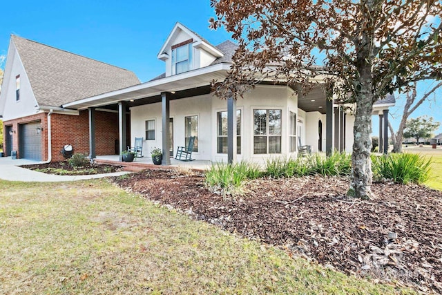 view of front of home featuring covered porch, a garage, and a front yard