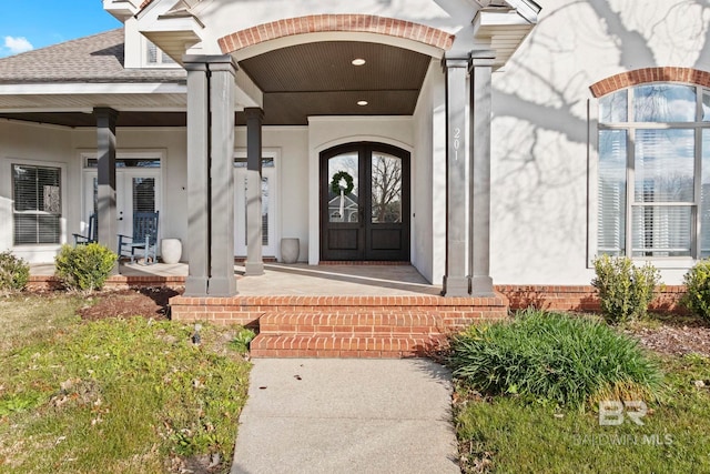 property entrance with covered porch and french doors