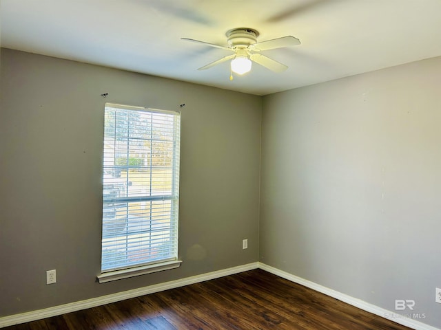 unfurnished room with a ceiling fan, dark wood-type flooring, and baseboards