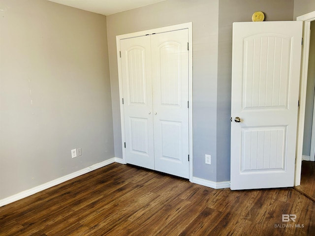 unfurnished bedroom featuring dark hardwood / wood-style flooring and a closet