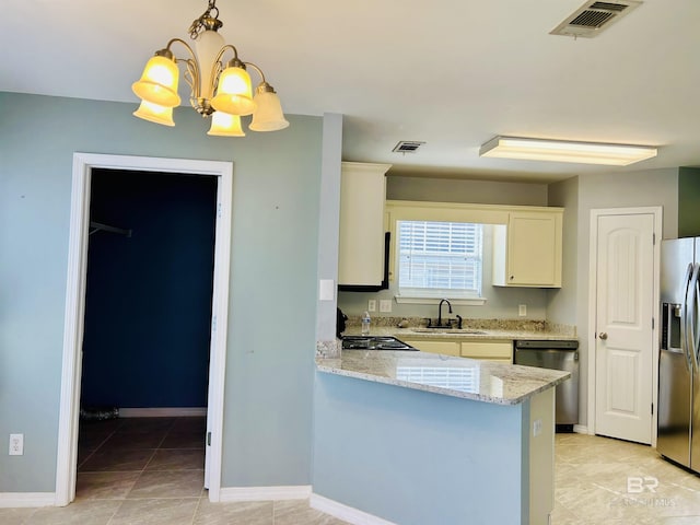 kitchen featuring sink, light stone counters, hanging light fixtures, appliances with stainless steel finishes, and kitchen peninsula