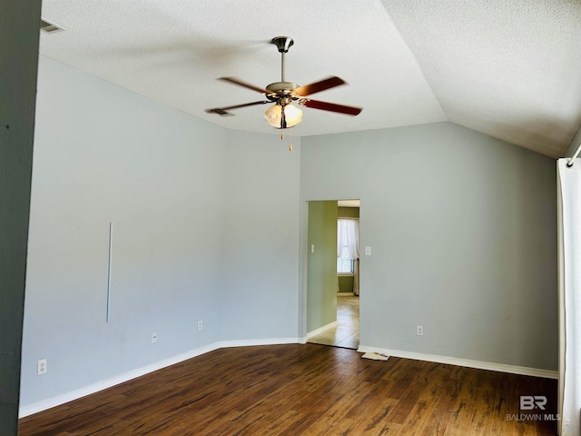 spare room featuring a ceiling fan, lofted ceiling, wood finished floors, and a textured ceiling