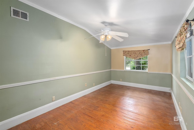 empty room featuring hardwood / wood-style flooring, vaulted ceiling, ceiling fan, and ornamental molding