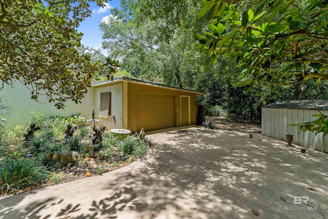 view of side of property featuring a garage and a storage shed