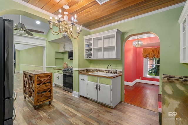 kitchen featuring appliances with stainless steel finishes, sink, hardwood / wood-style flooring, white cabinets, and hanging light fixtures