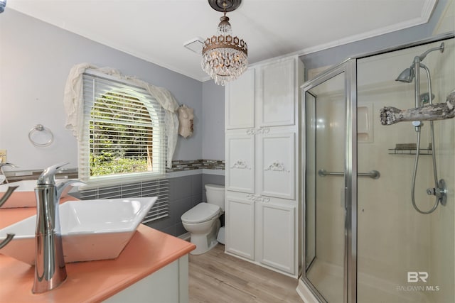 bathroom featuring wood-type flooring, sink, toilet, a shower with shower door, and a chandelier