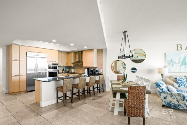 28107 Perdido Beach Blvd Unit D 503, Orange Beach, AL 36561 - kitchen with tasteful backsplash, light brown cabinetry, appliances with stainless steel finishes, a peninsula, and wall chimney exhaust hood