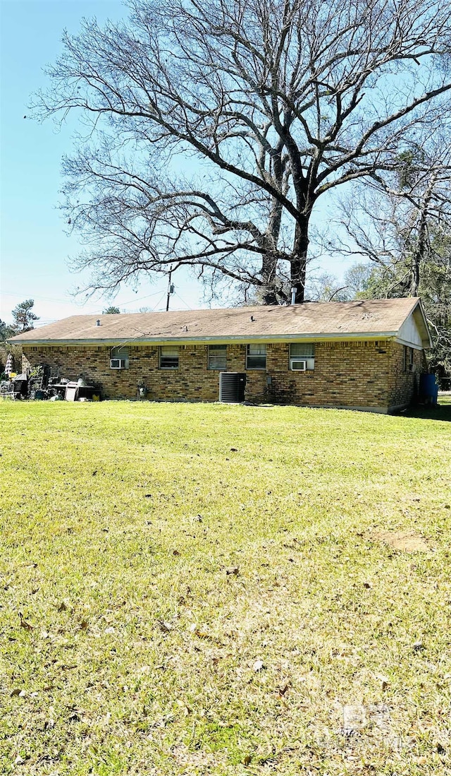 rear view of property with central air condition unit and a yard