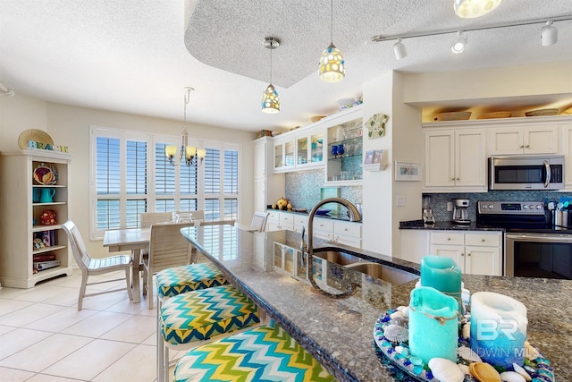 kitchen with tasteful backsplash, light tile patterned floors, white cabinets, stainless steel appliances, and a sink