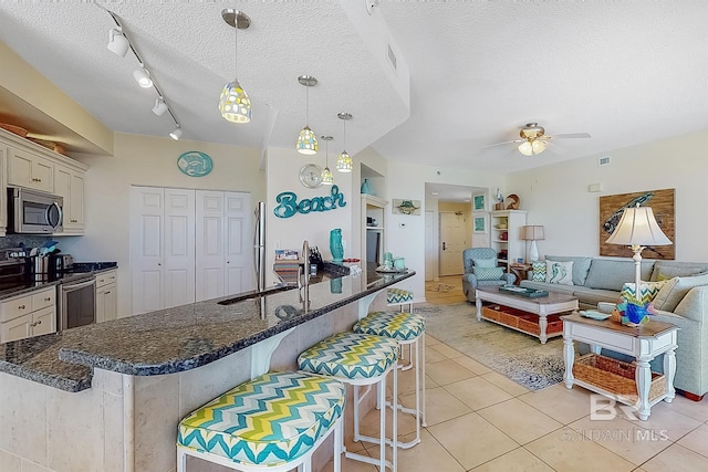 kitchen with light tile patterned floors, a breakfast bar area, a textured ceiling, and stainless steel appliances