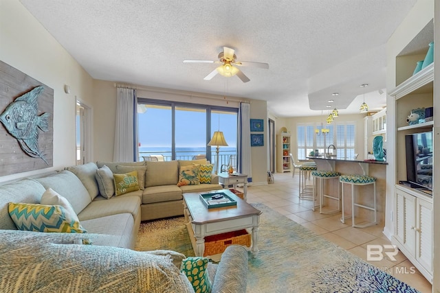 living room with light tile patterned flooring, a textured ceiling, and a ceiling fan