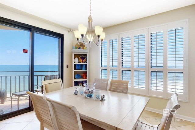 tiled dining space featuring baseboards, a water view, and a chandelier