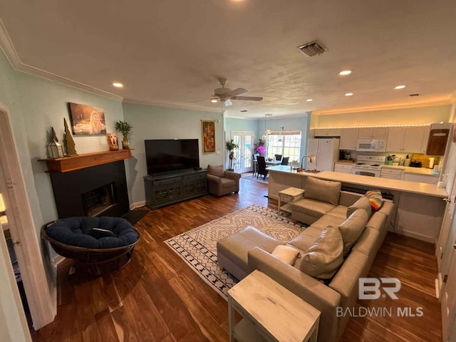 living room with ornamental molding, dark wood-type flooring, recessed lighting, a ceiling fan, and a fireplace